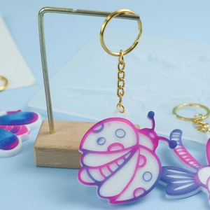 Vue détaillée d'un porte-clés coccinelle rose avec anneau doré sur un support