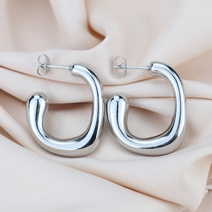 Macro detail of U-shaped silver geometric thick earrings on elegant silk background