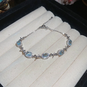 Elegant bow bracelet with light blue oval gemstones and silver-toned adjustable chain