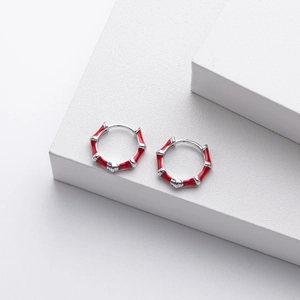 Macro detail of S925 silver bamboo hoop earrings with red enamel glaze on white blocks