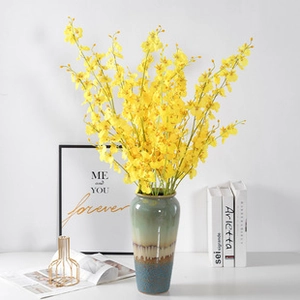 Detail of yellow artificial orchids in a ceramic vase for elegant home floral decor