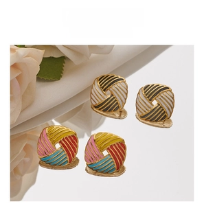 Macro detail of square stainless steel stud earrings with enamel woven pattern on silk