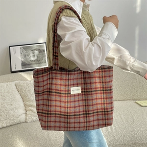 Model showcasing large plaid tote bag in a minimalist home setting for daily commute