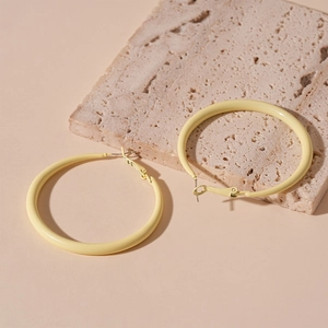 Detailed view of matte yellow round hoop earrings on a textured travertine stone