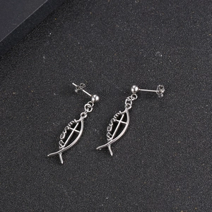 Silver titanium steel fish earrings with Jesus cross pendant on black surface