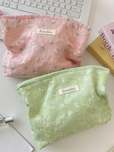 Pink and green floral lace makeup bags set on white desk with aesthetic accessories