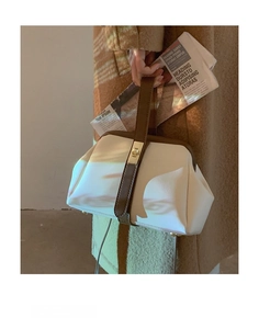 Detailed shot of two-tone cream and brown handbag with gold twist lock and frame closure