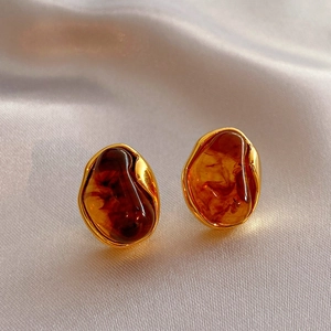 Detailed macro view of vintage gold earrings with amber-style stones on silk fabric