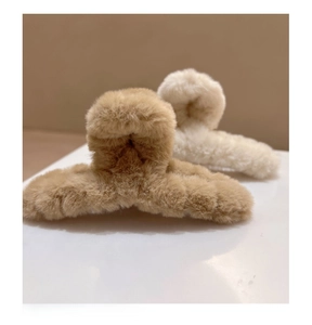 Gros plan de pinces à cheveux en peluche marron clair et blanc crème à texture douce
