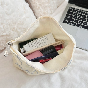 Flat lay of open floral toiletry bag with cosmetics on a white plush surface