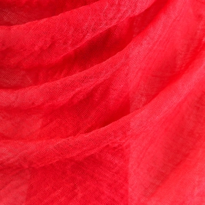 Macro detail of red crinkled cotton linen fabric texture with raw frayed edges