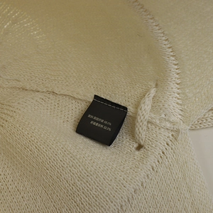 Detail shot of the white knitted fabric texture and care label showing material content