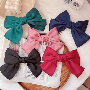Oversized JK style satin bow hair clips in five colors on a vintage wooden tray