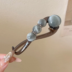 Detail of coffee resin twist clip featuring grey-blue cat eye beads and rhinestone accents