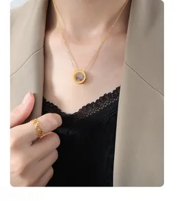 Close-up of gold chain necklace with round purple stone pendant and star ring