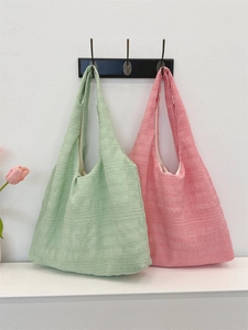 Detail of seersucker tote bag texture and wide handles in mint and pink colors