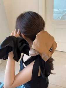 Detailed view of high-shine satin scrunchies in black and caramel silk fabric