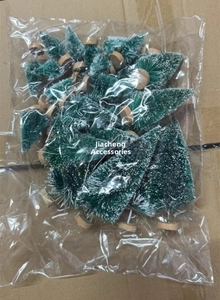 Close-up of mini snow-flocked Christmas trees with wooden bases in plastic packaging