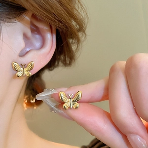 Detailed close-up of golden butterfly earring with fine wing textures on ear lobe