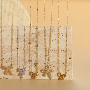 Collection de cinq colliers pendentifs nœuds en or et argent avec accents de zircon