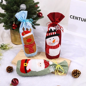 Three Christmas wine gift bags with Santa and Reindeer designs on a festive backdrop