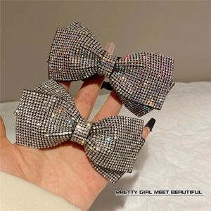 Close-up of bow hair clips with rainbow AB and clear rhinestones on black metal base