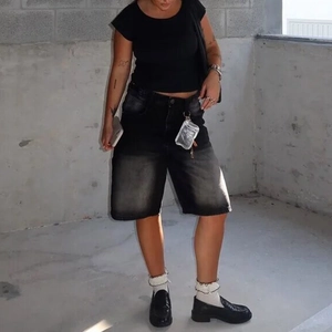Streetstyle-Aufnahme von locker sitzenden schwarzen Denim-Shorts mit Slippern