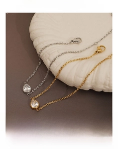 Macro detail of teardrop zircon bracelets in gold and silver on a ceramic tray