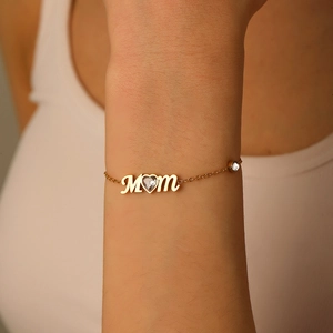 Gros plan détaillé du bracelet MOM plaqué or avec zircon coeur porté au poignet