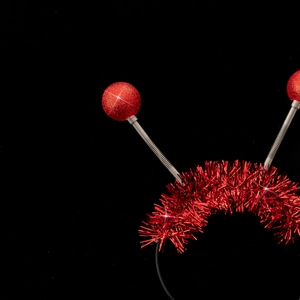 Close-up of red alien spring ball headband with metallic tinsel decor and glowing spheres