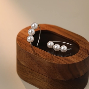 French vintage S925 silver earrings with three white pearls on a dark wooden stand