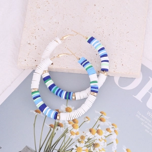 Detail view of Bohemian hoop earrings with colorful clay beads on artistic background
