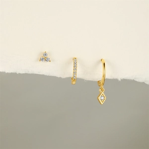 Detailed view of gold S925 silver earrings with zircons on minimalist textured paper