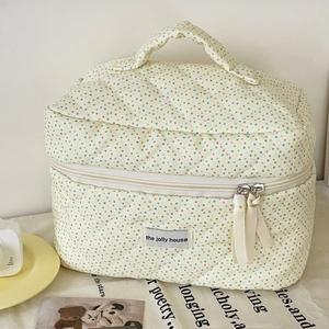Quilted floral cotton cosmetic bag with handle, ribbon zipper, and the jolly house label