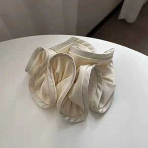 Close-up of cream satin scrunchie with layered ruffles and soft silk texture details