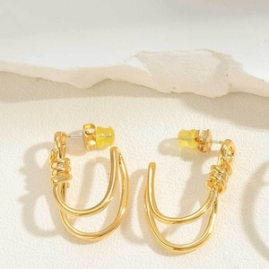 Detailed close-up of golden double-layer U-shaped earrings with a twisted knot design