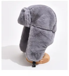 Close-up of thick grey faux fur trapper hat with black ear flap buckle on wooden stand
