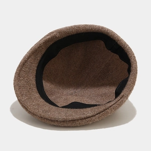 Interior view of a brown wool beret cap showing the knitted texture and black sweatband