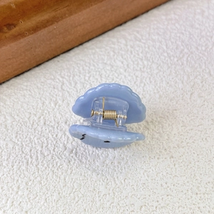 Detailed view of sky blue shell-shaped hair claw clip with golden metal spring