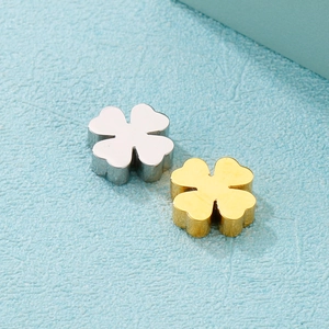 Détail des pendentifs trèfle en métal doré et argenté sur fond texturé bleu