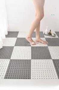 Close-up of TPE bathroom drainage mat with grey and white interlocking tiles in a shower