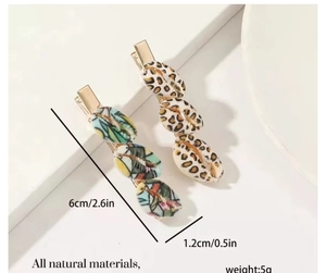 Detailed view of hair clips with shell patterns and gold metal base displayed on a stand
