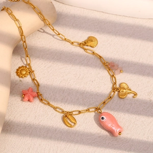 Detail of gold paperclip chain necklace with pink starfish and seashell charms