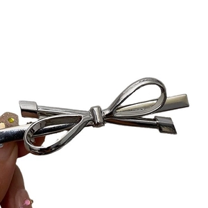 Silver metallic bow hair clip held by hand, elegant hair accessory for women