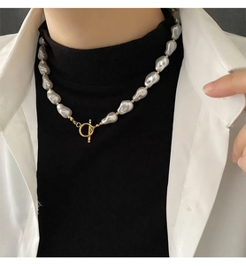 Detailed view of grey baroque pearl necklace with golden OT clasp worn by a model