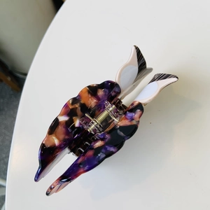 Detail view of large marble pattern hair claw clip with golden metal spring mechanism