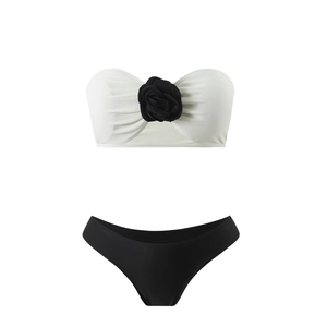 Detail of white bandeau bikini top with a large black fabric flower and black bottoms