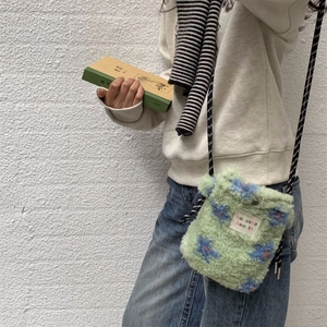 Light green plush crossbody bag with blue floral patterns and woven rope strap