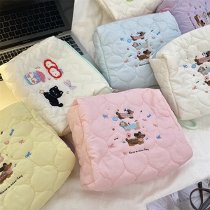 Close-up of cream quilted cotton pouch featuring delicate floral and puppy embroidery
