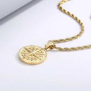 Gros plan d'un pendentif boussole doré avec gravure NSEW sur surface métallique